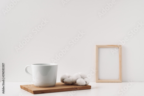 Frame  cotton and a cup on a wooden board  white background. Mock up  copy space. Folk.