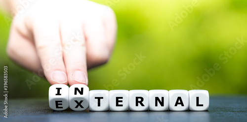Hand turns dice and changes the word external to internal.