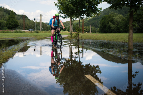 Young athlete woman riding a bicycle on a road through the water. © Petra