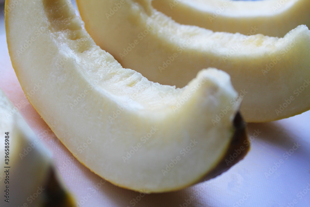 Ripe melon, pitted and cut into slices, close-up, side view. The slices are laid out in a row on a gray surface. Summer season. Ripe melon, pitted and cut into slices, close-up, side view. The slices are laid out in a row on a gray surface. Summer season.