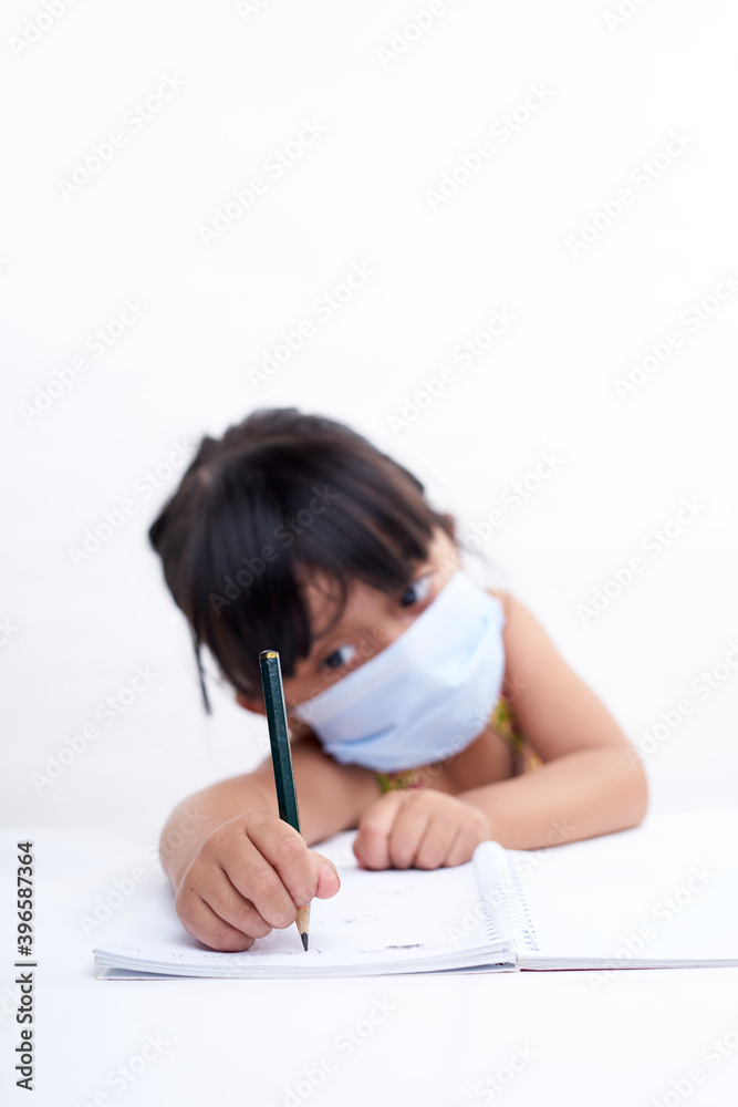 Close-up little girl hand writing in notebook, Wearing a protective face mask Close-up little girl hand writing in notebook, Wearing a protective face mask