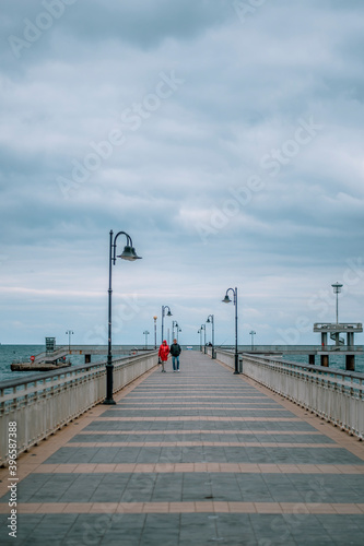 A couple taking a walk on a bridge in the sea. Winter autumn season.