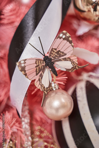 beautiful Christmas decorations on the Christmas tree: pink butterfly, ball and ribbon