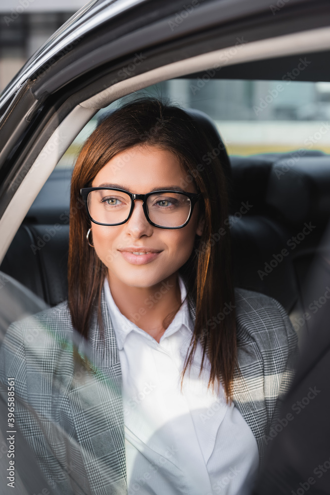 stylish, businesswoman in eyeglasses looking out from open window in car on blurred foreground stylish, businesswoman in eyeglasses looking out from open window in car on blurred foreground