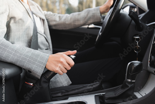 partial view of businesswoman shifting hand brake lever while steering car on blurred  © LIGHTFIELD STUDIOS