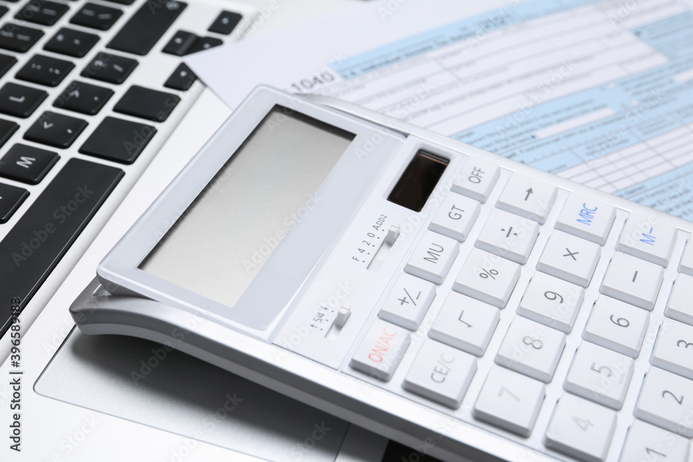 Calculator and document on laptop, closeup. Tax accounting Calculator and document on laptop, closeup. Tax accounting
