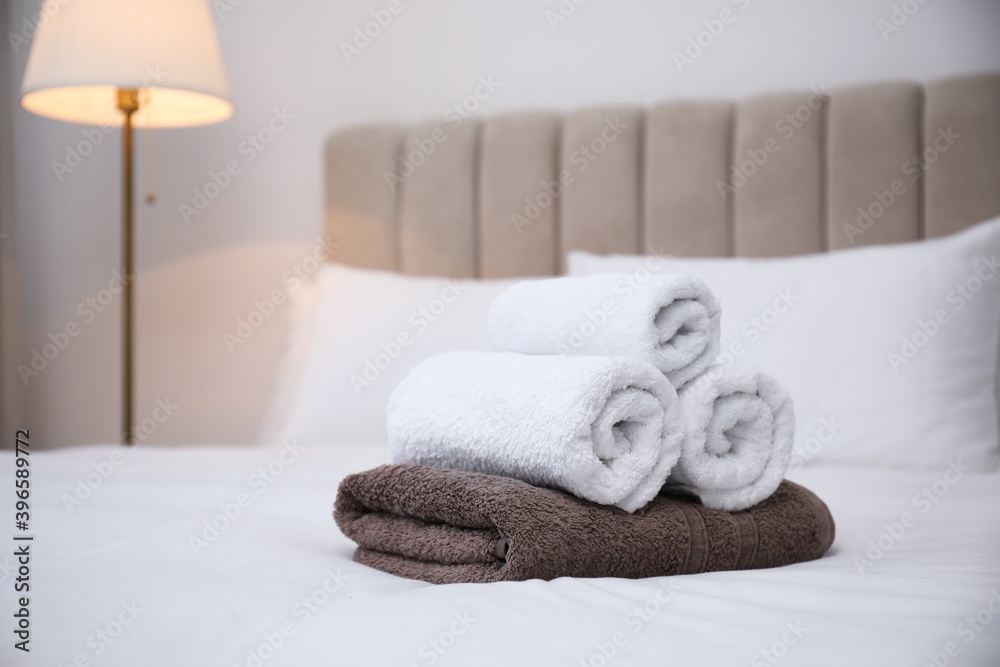 Soft clean towels on white bed indoors. Space for text Soft clean towels on white bed indoors. Space for text