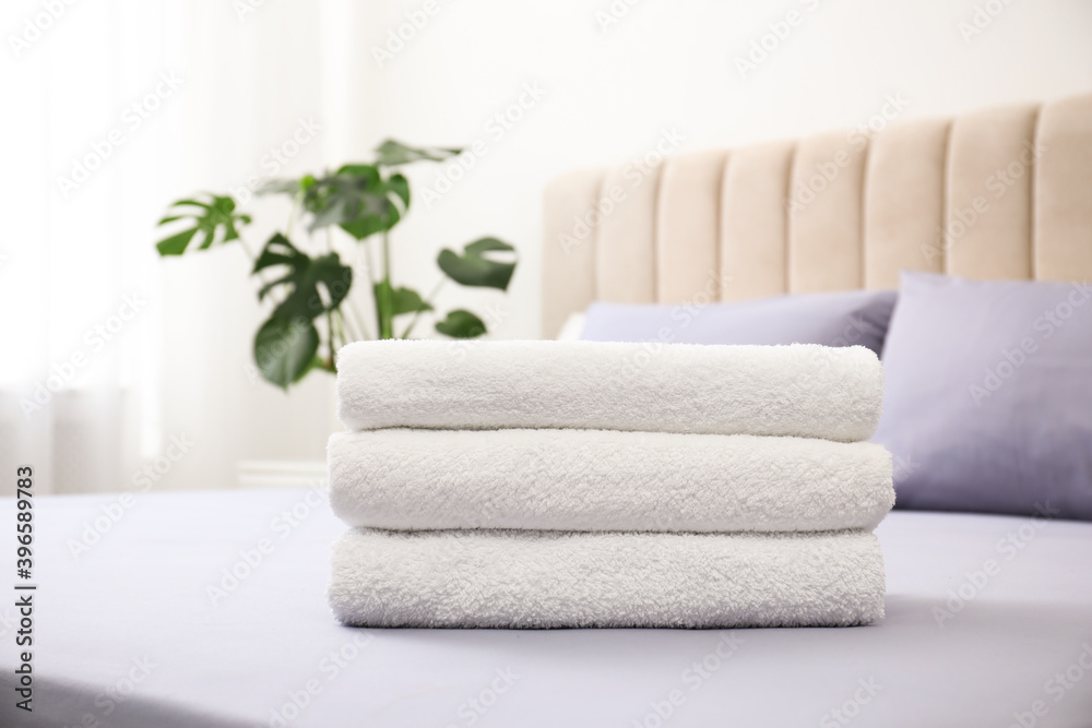Stack of clean towels on bed indoors