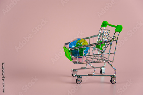 small empty shopping cart with globe on pink background
