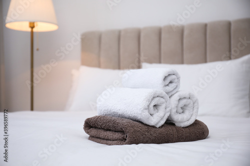 Soft clean towels on white bed indoors. Space for text