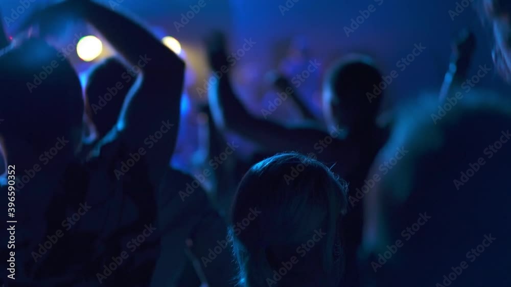 Concept of the party and entertainment. Rock music. The crowd at music concert, the audience raising their hands up. Gig in a night club, people having fun and enjoying dancing on the dance floor. Concept of the party and entertainment. Rock music. The crowd at music concert, the audience raising their hands up. Gig in a night club, people having fun and enjoying dancing on the dance floor.