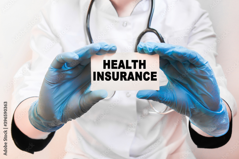 The doctor's blue - gloved hands show the word HEALTH INSURANCE - . a gloved hand on a white background. Medical concept. the medicine The doctor's blue - gloved hands show the word HEALTH INSURANCE - . a gloved hand on a white background. Medical concept. the medicine