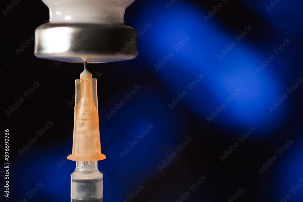 medical syringe cannula with vaccine vial, blue background. macro medical syringe cannula with vaccine vial, blue background. macro