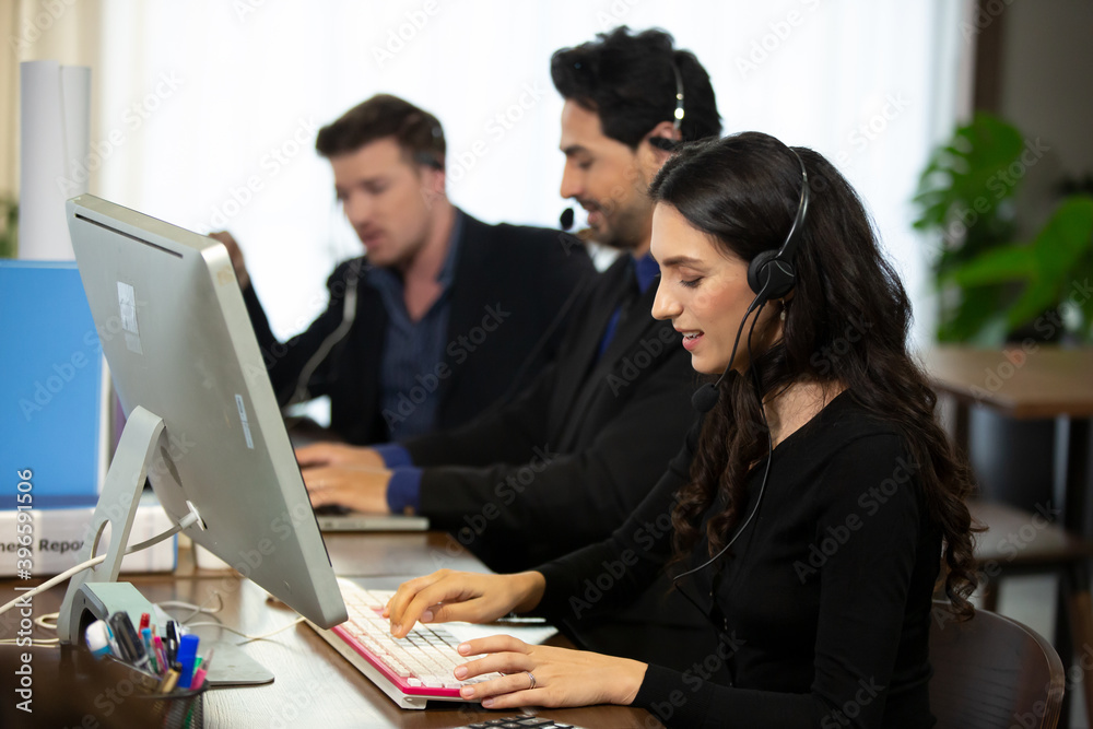 Smiling customer support operator with hands-free headset working in the office. Smiling customer support operator with hands-free headset working in the office.