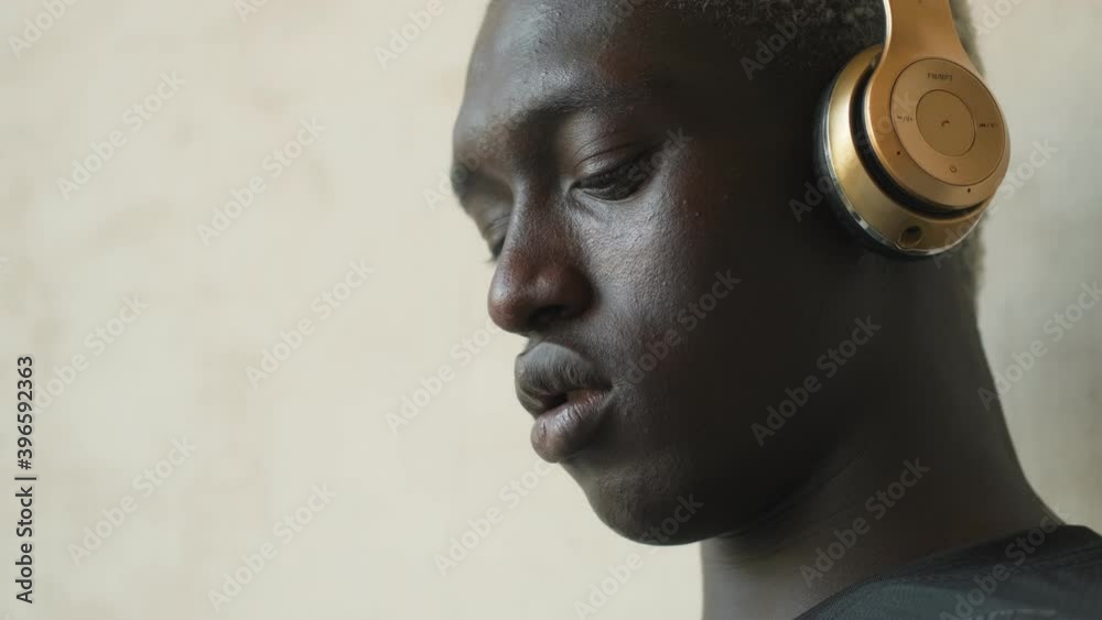 A close-up view of an african american man with headphones is using his smartphone indoors A close-up view of an african american man with headphones is using his smartphone indoors