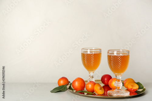 Delicious plum liquor and ripe fruits on light table. Homemade strong alcoholic beverage photo