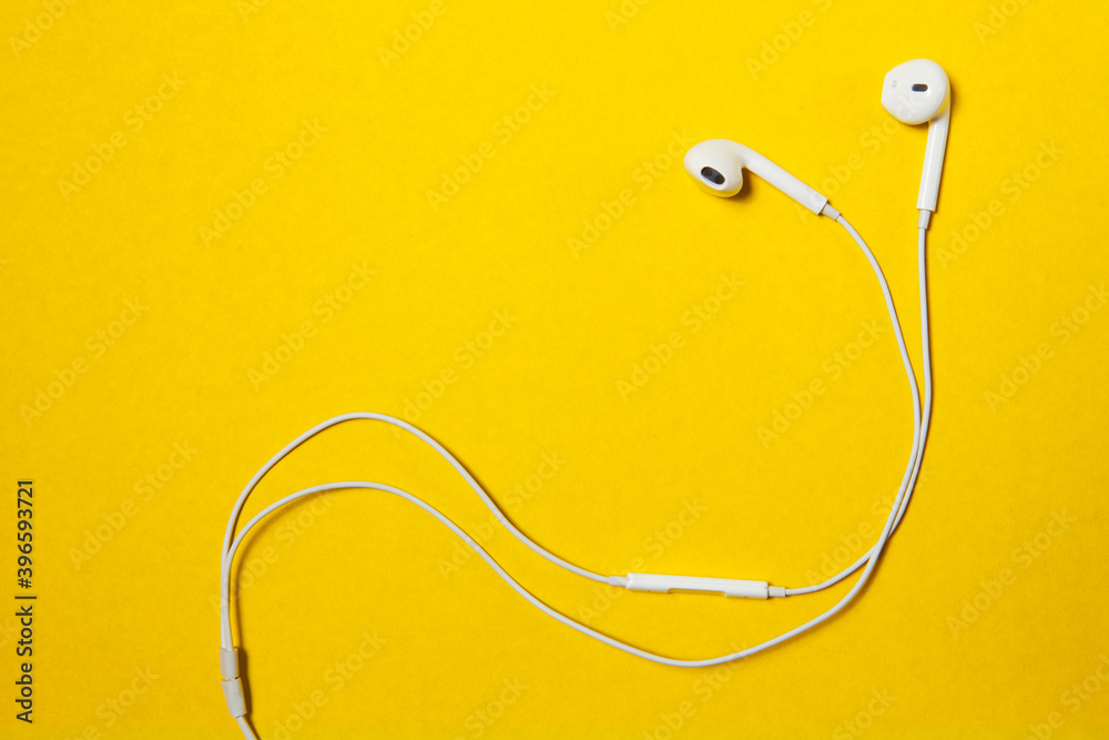 White wired headset on yellow background with place for text