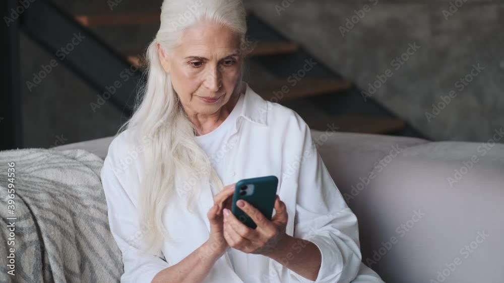 Smiling senior woman using mobile phone indoors at home Smiling senior woman using mobile phone indoors at home