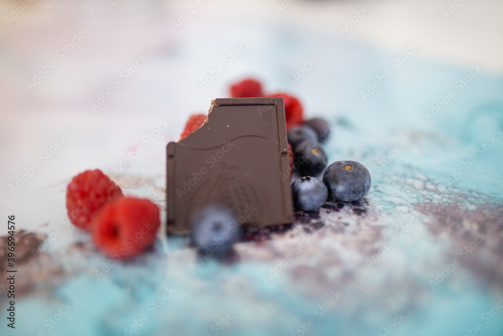 Bitten chocolate bar and berries on a colorful placemat Bitten chocolate bar and berries on a colorful placemat