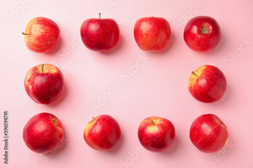 Frame made of fresh ripe red apples on pink background, flat lay. Space for text