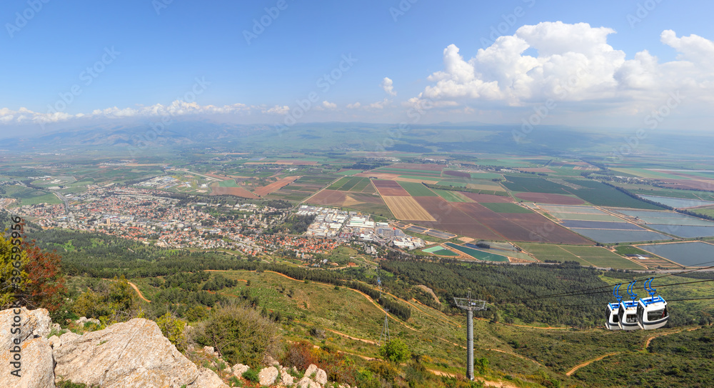 Panoramic view from Manara Cliff on Hula Valley. Kiryat Shmona city  and beautiful farming landscape with agricultural land. Cableway cabins go up to the mountain. Upper Galilee. Northern Israel