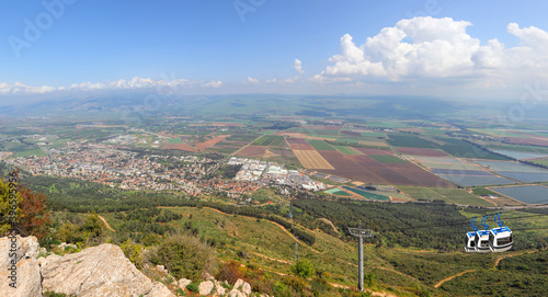 Panoramic view from Manara Cliff on Hula Valley. Kiryat Shmona city and beautiful farming landscape with agricultural land. Cableway cabins go up to the mountain. Upper Galilee. Northern Israel