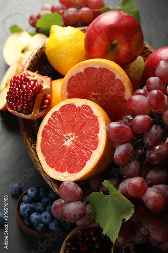 Fototapeta Naklejka Na Ścianę i Meble -  Wicker basket with different fruits berries on black table, closeup