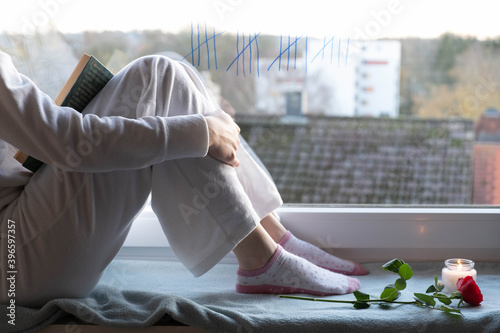 the girl is bored in quarantine on the windowsill next to a rose photo