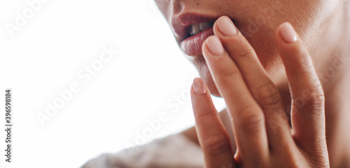 herpes on the lips, part of a woman's face with finger on lips with herpes, beauty concept 