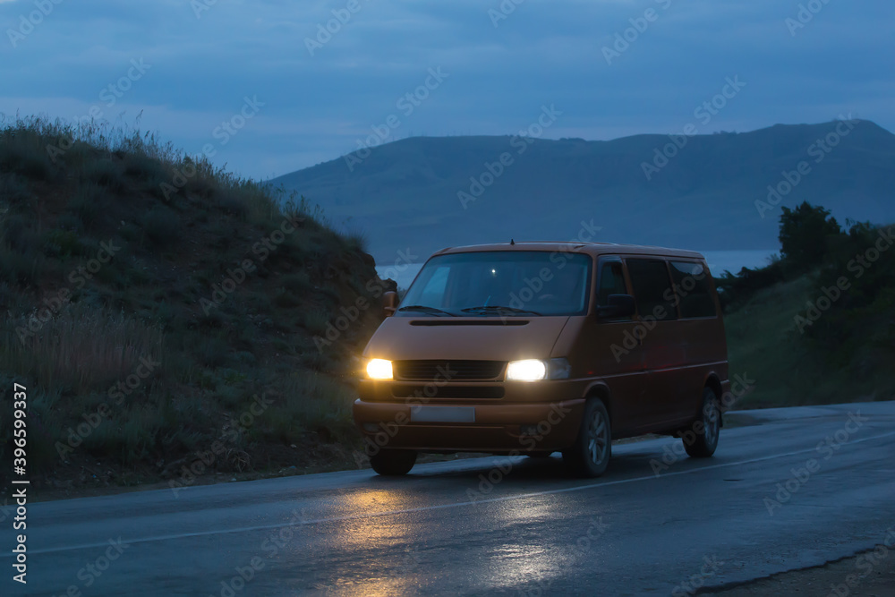 Minivan moves at night along a winding mountain road
