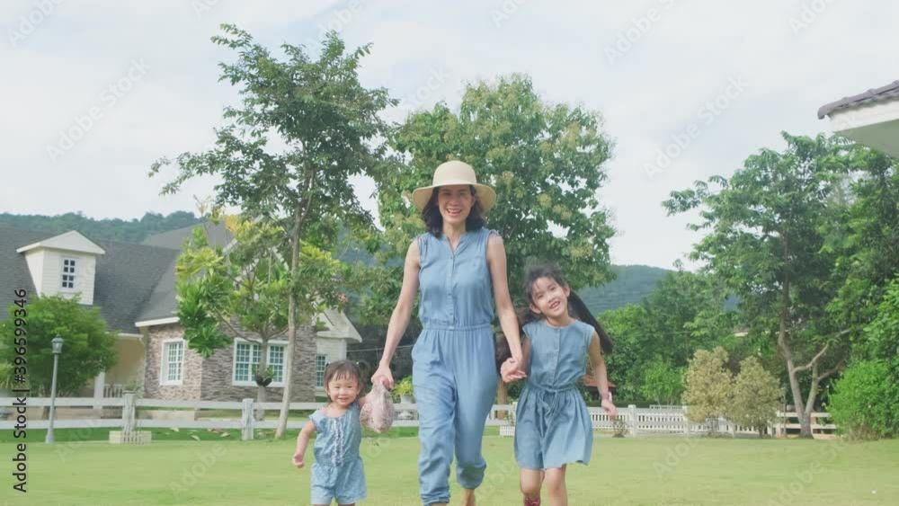 Asian young mother playing with her daughters by running in backyard. Asian young mother playing with her daughters by running in backyard.