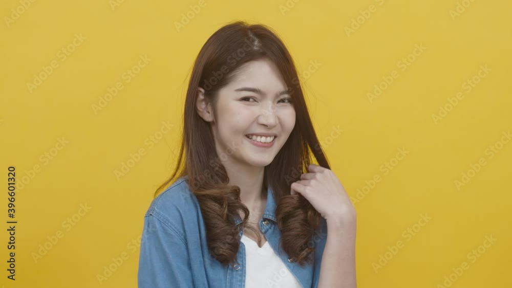 Portrait of asian young woman wearing white t-shirt and blue jean jecket feeling happy, funny, enjoy and looking at camera with joyful and charming smile. Asian woman on yellow background studio shot Portrait of asian young woman wearing white t-shirt and blue jean jecket feeling happy, funny, enjoy and looking at camera with joyful and charming smile. Asian woman on yellow background studio shot