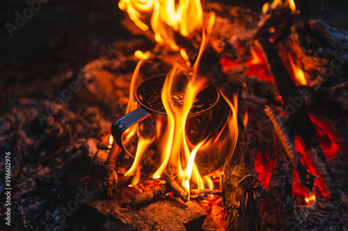 Close up of tea in metal mug heats up in bonfire