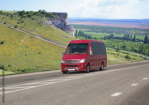 Red minibus moves on a road in the mountains