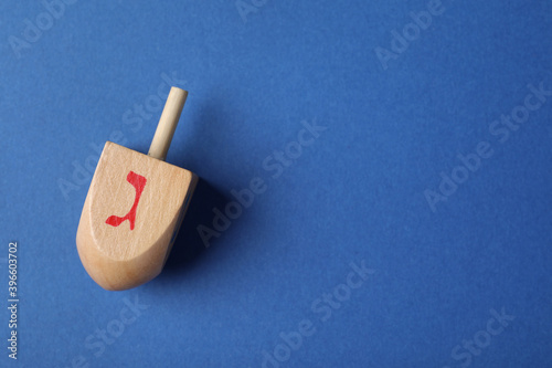 Hanukkah traditional dreidel on blue background, top view. Space for text