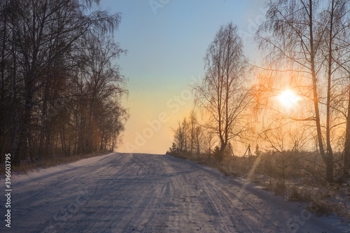 Winter snowy road in the morning at sunset