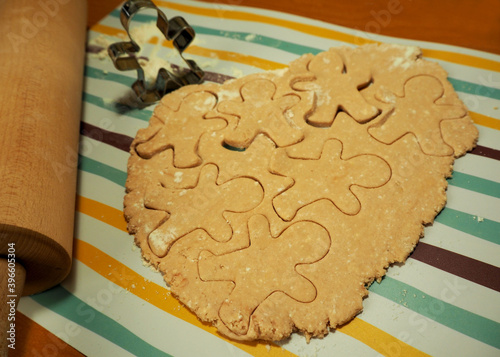 raw cookies made from cottage cheese and rice flour with date syrup in the form of a gingerbread man with a metal shape and a wooden rocking chair on the side during cooking at home side view