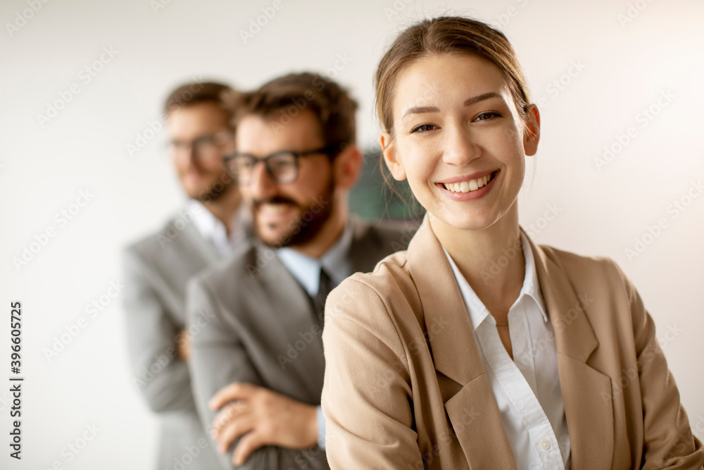 Smiling young business woman standing with group of corporate colleagues in a row together Smiling young business woman standing with group of corporate colleagues in a row together