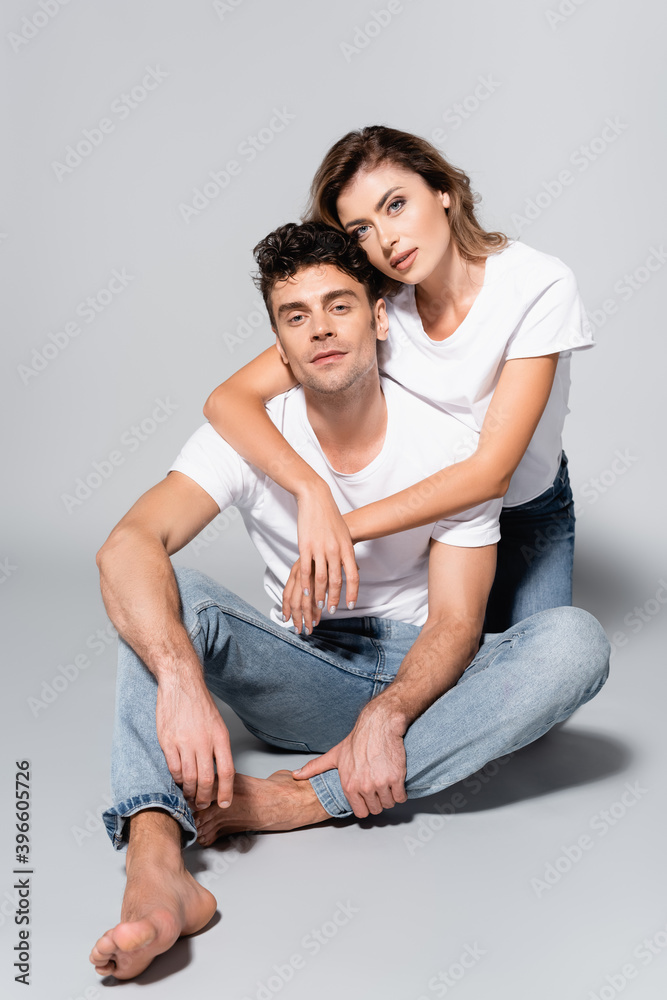 couple in white t-shirts embracing isolated on grey couple in white t-shirts embracing isolated on grey
