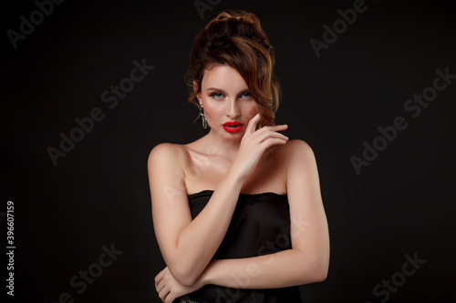Beauty portrait of elegant young woman. Glamour makeup. Face of the beautiful woman with long brown curly hair posing at studio over dark background. Sensual portrait.