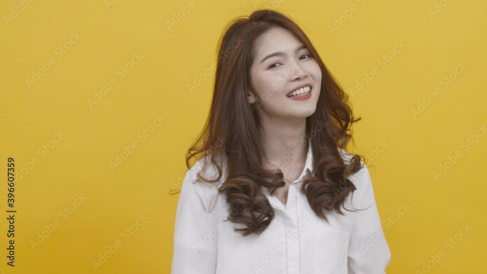Portrait of asian young woman wearing white t-shirt feeling happy, funny, enjoy and looking at camera with joyful and charming smile. Asian woman on yellow background studio shot Portrait of asian young woman wearing white t-shirt feeling happy, funny, enjoy and looking at camera with joyful and charming smile. Asian woman on yellow background studio shot