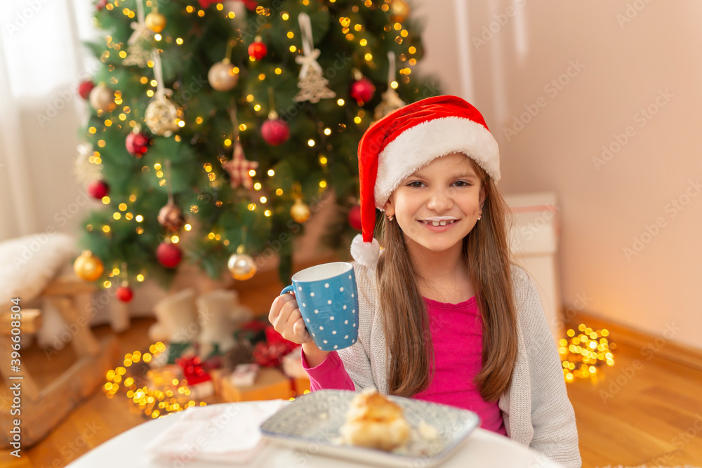 Little girl eating breakfast by the Christmas tree Little girl eating breakfast by the Christmas tree