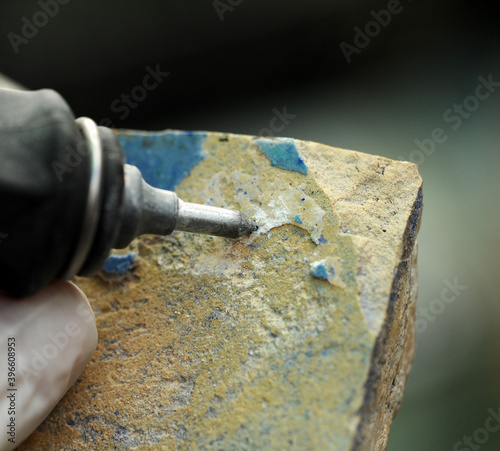 Limpieza a mano de un azulejo antiguo con micropercutor. Restauración y conservación de cerámica antigua photo