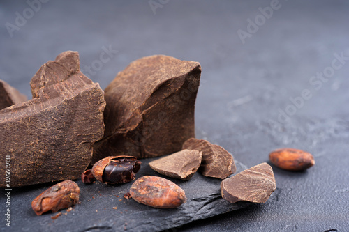 Cocoa mass liquor, beans on slate stand, gray concrete background. Confectionery, menu, recipe concept. Close-up, copy space