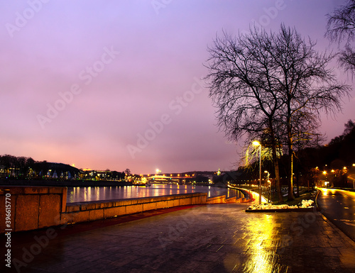 Evening city, embankment, winter, trees without leaves. © Yury
