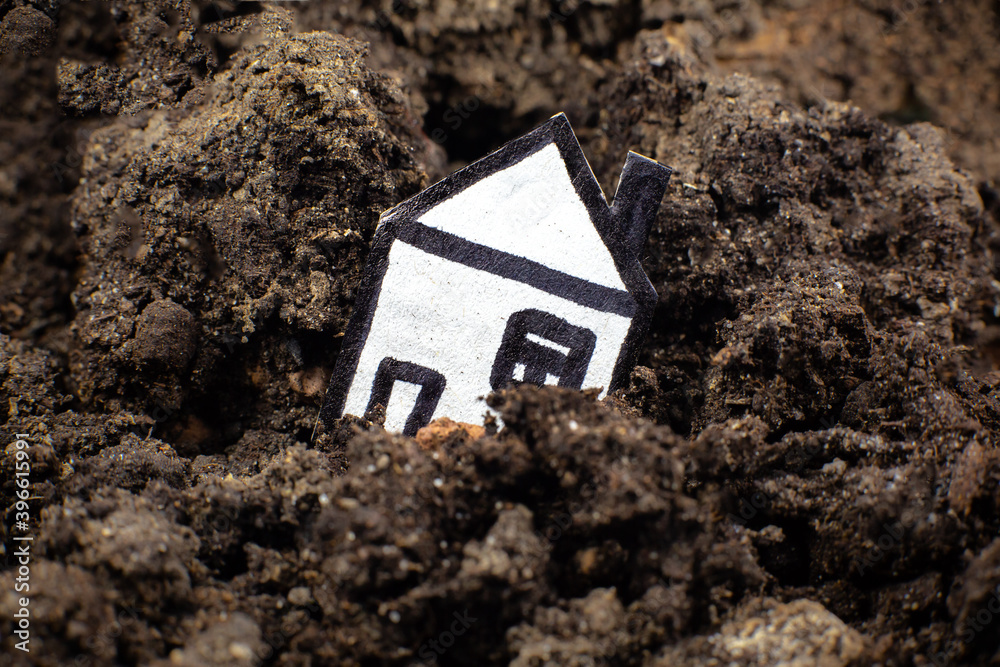House in the soil, falling into a crack in the earth. Сoncept of earthquake and loss of a house. Сredit debts. House in the soil, falling into a crack in the earth. Сoncept of earthquake and loss of a house. Сredit debts.