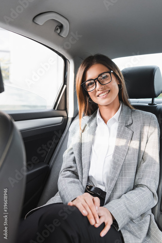 happy, businesswoman smiling at camera while riding in car on blurred foreground © LIGHTFIELD STUDIOS