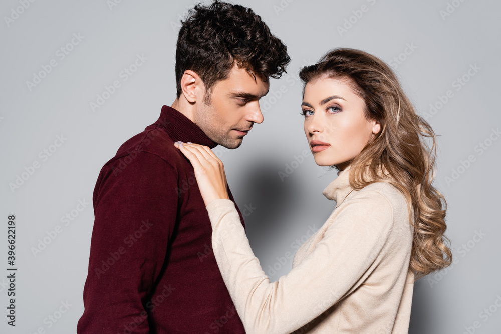 side view of young couple in turtleneck jumpers isolated on grey side view of young couple in turtleneck jumpers isolated on grey