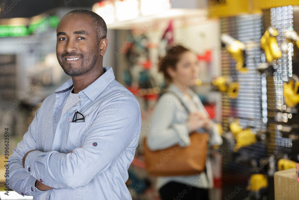 hardware store salesman standing next to shelves hardware store salesman standing next to shelves