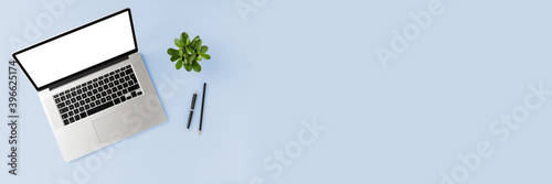 Modern business background with laptop with empty screen and accessories on blue table. Office desktop. Top view. Banner